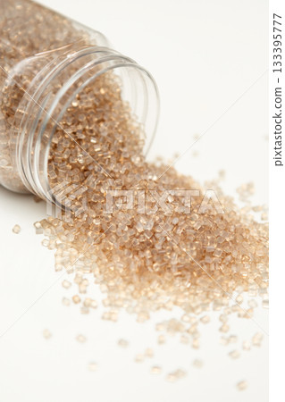 Clear Polymer Pellets Flowing from Plastic Container 133395777