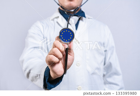 Doctor hands holding stethoscope with European Union flag. European Union health and care concept Doctor hands holding stethoscope with European Union flag. European Union health and care concept 133395980
