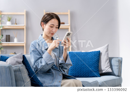 A woman who manipulates a smartphone in the living room A woman who manipulates a smartphone in the living room 133396092