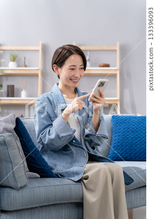 A woman who manipulates a smartphone in the living room A woman who manipulates a smartphone in the living room 133396093