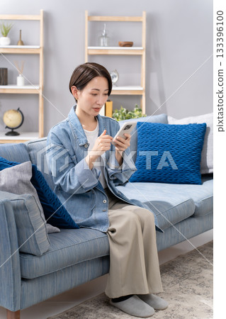 A woman who manipulates a smartphone in the living room 133396100