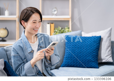 在客廳操縱智能手機的女人 133396106