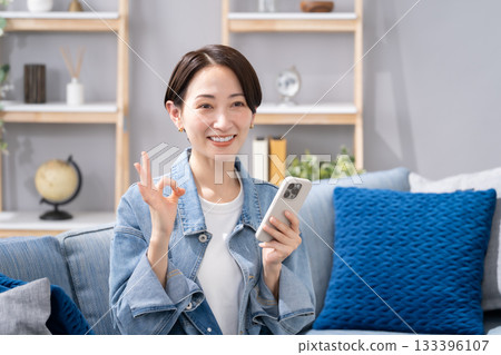 一位女士在客廳操作智慧型手機，沒問題。 133396107