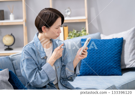 Angry woman holding smartphone in living room 133396120