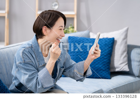 Woman holding a smartphone in the living room 133396128