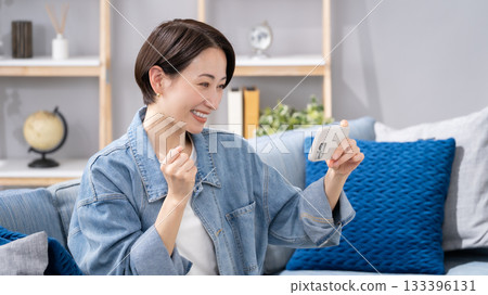 Woman holding a smartphone in the living room Woman holding a smartphone in the living room 133396131