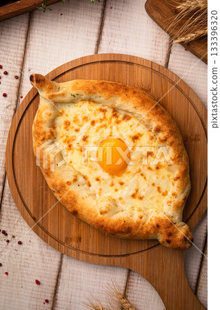 Hot khachapuri with egg on wooden board Hot khachapuri with egg on wooden board 133396320