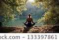 Woman in lotus pose practicing mindfulness and wellness by tranquil lake. 133397861