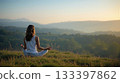 Woman meditating yoga pose overlooking tranquil mountain sunrise. 133397862