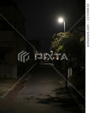 An alleyway at night with streetlights shining 133398638