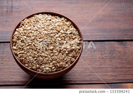 Raw Rolled Oats in Bowl on Dark Wooden Table Copy Space 133399241