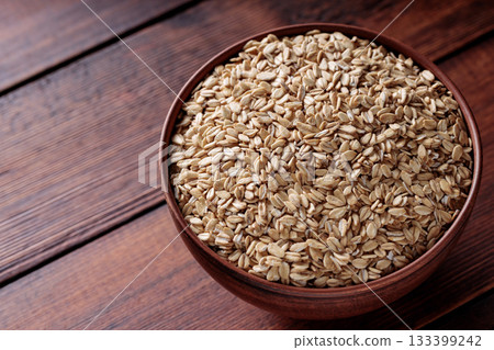Raw Rolled Oats in Bowl on Dark Wooden Table Copy Space 133399242