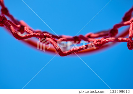 A red basketball net outlined against a clear sky. 133399613