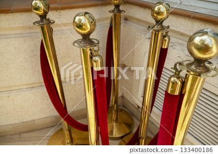 Gold colored metal stanchions with red velvet rope for crowd control Gold colored metal stanchions with red velvet rope for crowd control 133400186