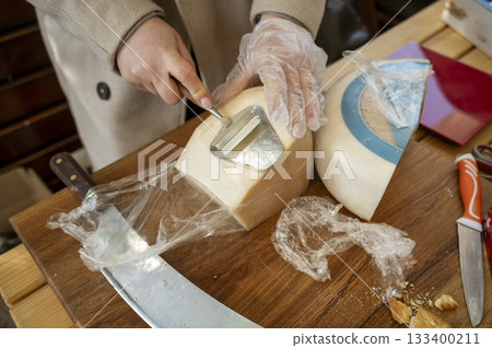 Close-up of the hands of a vendor cutting cheese at a farmers market. Close-up of the hands of a vendor cutting cheese at a farmers market. 133400211