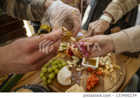 Cheese tasting at a farmers market, close-up of the hands of a seller and a buyer 133400234