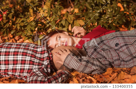 young couple in love lying on the ground in autumn park on yellow foliage 133400355