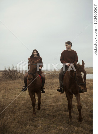 Young romantic couple horse riding, against the background of a field of autumn grass. 133400507