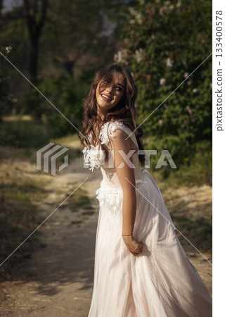 Stunning bride gracefully poses in a spring park, among blossoming trees. exuding elegance, Stunning bride gracefully poses in a spring park, among blossoming trees. exuding elegance, 133400578