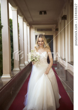 beautiful blonde bride walks along the opened gallery of the hotel with a bouque beautiful blonde bride walks along the opened gallery of the hotel with a bouque 133400627