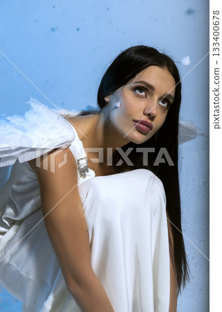 Studio portrait of sexy blonde in white long elegant dress and angel wings, she poses sensually  133400678