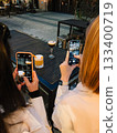 Two women are taking photos of cocktails with their smartphones, sitting at table in modern bar, capturing moment and drinks. Women photographing colorful cocktails Trendy beverage experience 133400719