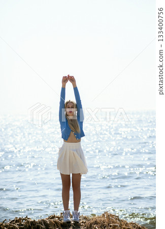 Beautiful blonde girl stands on a sandy beach in sunny weather. Sunset Beautiful blonde girl stands on a sandy beach in sunny weather. Sunset 133400756