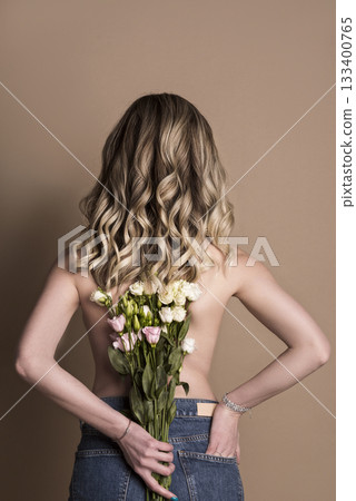 studio shot of a girl in jeans, with a bare back and flowers. studio shot of a girl in jeans, with a bare back and flowers. 133400765