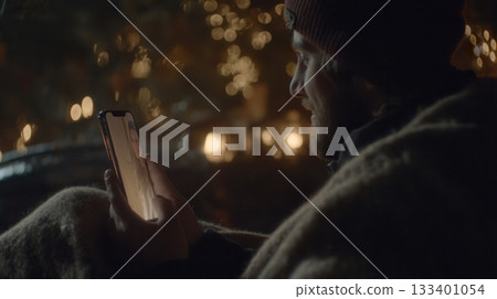 A man has a video call with a woman at night, wrapped in a cozy blanket. The warm, intimate mood is perfect for themes of connection, love, technology, and long-distance relationships. 133401054