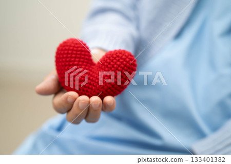 Asian elder senior woman patient holding red heart in hospital. Asian elder senior woman patient holding red heart in hospital. 133401382