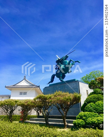 A castle and a statue of a mounted warrior against the blue sky 133402564