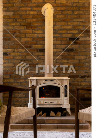 Brick fireplace with a wood burning stove and two chairs. Brick fireplace with a wood burning stove and two chairs. 133404373