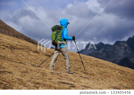 Backpacking woman hiking on high altitude mountain top 133405456