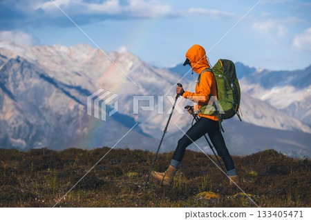 Backpacking woman hiking on sunset high altitude mountain top 133405471