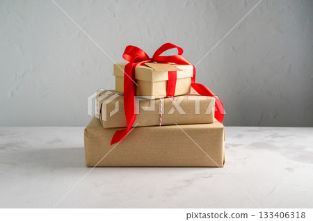 Festive Christmas craft gift boxes with red bows on bright background, Christmas background 133406318