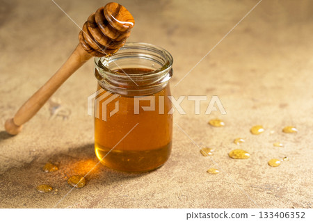 Jar of honey with wooden dipper, sweet liquid, neutral background Jar of honey with wooden dipper, sweet liquid, neutral background 133406352