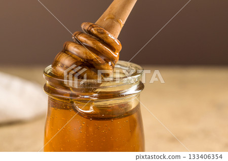 Jar of honey with wooden dipper, sweet liquid, neutral background Jar of honey with wooden dipper, sweet liquid, neutral background 133406354