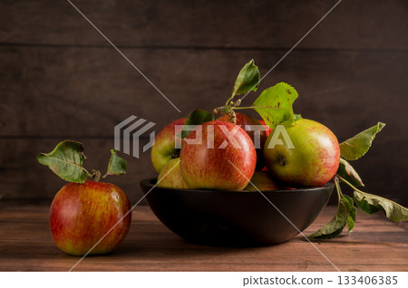 Freshly picked red apples in a bowl, rustic wooden background 133406385