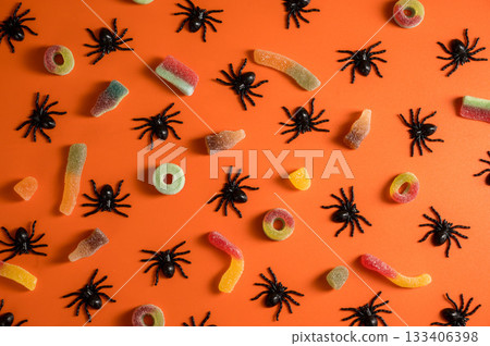 Halloween candies and spiders over orange background. Flat lay, abstract background 133406398