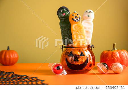 Halloween abstract background, with pumpkin bowl, candy lollies, orange background 133406431