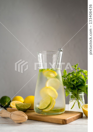A glass jug with lemonade with lemons, limes and fresh mint, summer drink, copy space A glass jug with lemonade with lemons, limes and fresh mint, summer drink, copy space 133406436