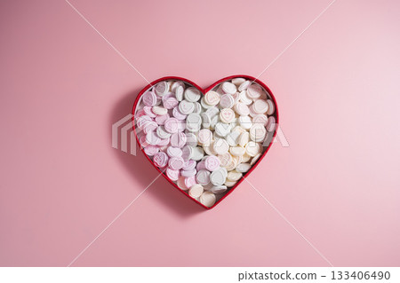 Heart-shaped candies in heart shaped box, over pink background, abstract food love background 133406490