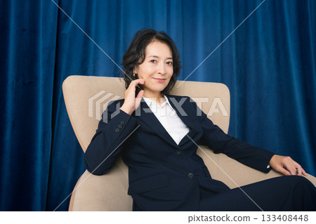 Middle-aged businesswoman sitting on a large chair Middle-aged businesswoman sitting on a large chair 133408448