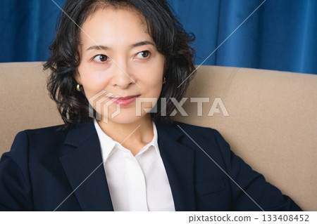 坐在大椅子上的中年女商人 133408452