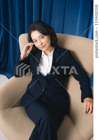 Middle-aged businesswoman sitting on a large chair Middle-aged businesswoman sitting on a large chair 133408508