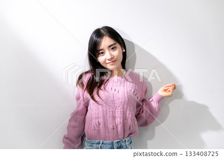 Young woman posing in the sunlight in front of a white wall Young woman posing in the sunlight in front of a white wall 133408725