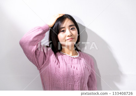 Young woman posing in the sunlight in front of a white wall Young woman posing in the sunlight in front of a white wall 133408726