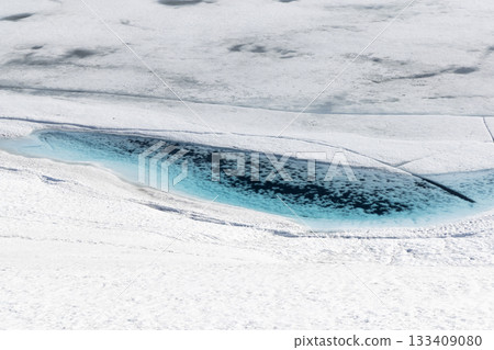Winter landscape features bright blue water surrounded by snow at Leirvassbu in Jotunheimen National Park during a sunny day Winter landscape features bright blue water surrounded by snow at Leirvassbu in Jotunheimen National Park during a sunny day 133409080