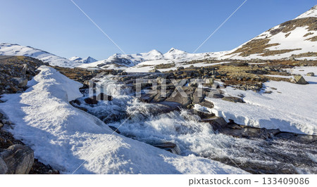 Winter landscape showing snowy terrain and flowing water at Leirvassbu in Jotunheimen National Park Winter landscape showing snowy terrain and flowing water at Leirvassbu in Jotunheimen National Park 133409086