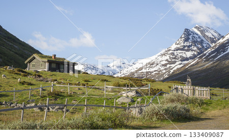 Snowy mountains frame a cozy cabin at Leirvassbu in Leirdalen, Jotunheimen National Park during clear skies Snowy mountains frame a cozy cabin at Leirvassbu in Leirdalen, Jotunheimen National Park during clear skies 133409087